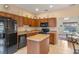 Kitchen featuring brown cabinets, an island, and black appliances with a view to the living room at 1407 S Palmetto Ave, Sanford, FL 32771