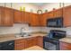 Kitchen featuring wood cabinets, a double sink, and black appliances at 1407 S Palmetto Ave, Sanford, FL 32771
