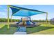 Community playground with colorful equipment and a protective shade covering at 1614 Teagan Ln, Winter Haven, FL 33884