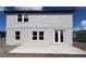 Rear exterior with a modern patio, white siding, and symmetrical window design under a bright sky at 1646 Cane Bamboo Drive, St Cloud, FL 34771