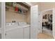Functional laundry room with washer, dryer, shelving, and easy access to office at 182 Westmoreland Cir, Kissimmee, FL 34744