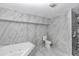 Bright bathroom featuring marble tiling, jetted tub, modern toilet, and enclosed shower at 1836 Se 6Th Ave, Ocala, FL 34471