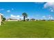 Large backyard with green grass, a tree, and other houses nearby beneath a blue sky with clouds at 200 Cimarron Dr, Kissimmee, FL 34759