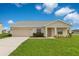 Charming single-story home featuring a well-manicured lawn and neutral-toned exterior under a bright, partly cloudy sky at 200 Cimarron Dr, Kissimmee, FL 34759