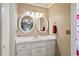 Bathroom with dual sinks, white cabinetry, and decorative mirrors and lighting at 2112 Plymouth Sorrento Rd, Apopka, FL 32712