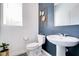 Stylish powder room with a navy accent wall, sleek pedestal sink, and modern decor, blending form and function beautifully at 224 Nine Iron Dr, Davenport, FL 33896