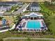 Aerial view of a community pool with lounge chairs, umbrellas, and a nearby playground, surrounded by townhomes at 224 Nine Iron Dr, Davenport, FL 33896