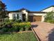 Inviting single-Gathering home featuring a brick driveway, manicured landscaping, and a neutral-toned facade at 312 Irving Bend Dr, Groveland, FL 34736