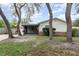 Inviting home featuring brick accents, a screened front porch, and a well-manicured lawn with mature trees at 407 Ventura Dr, Sanford, FL 32773