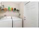 Practical laundry area with a washer, dryer, and shelving for storage with white door at 436 Azores Ave, Orlando, FL 32811