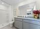 Stylish bathroom features gray vanity with granite countertop, large mirror and shower with white surround at 6006 Galloping Dr, Apopka, FL 32712