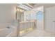 Bathroom featuring double sinks, a tub, and a walk-in shower with elegant white tile and glass block at 6609 Crenshaw Drive, Orlando, FL 32835