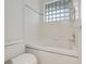 Bright bathroom with updated tile work, toilet, and glass block window for privacy at 6609 Crenshaw Drive, Orlando, FL 32835