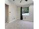 This bedroom has neutral walls, carpet, a ceiling fan, and a window with a view to the backyard at 6609 Crenshaw Drive, Orlando, FL 32835