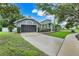 Home with a gray exterior, well-manicured lawn, and a spacious driveway leading to a two-car garage at 6609 Crenshaw Drive, Orlando, FL 32835