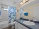 Bathroom with a shower-tub combination, floral shower curtain, large mirror, and single vanity at 9034 Paolos Place Paolos Place, Kissimmee, FL 34747