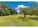 A large grass yard with mature trees near a white fence, offering lots of space at 9329 7Th Ave, Orlando, FL 32824