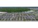 Aerial view showcasing the community with many homes, a pond, and woods in the background at 9941 Introduction Way, Orlando, FL 32832