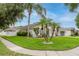 A charming single-story home boasts well-manicured landscaping, lush green lawn, and a bright white exterior at 10001 Newington Dr, Orlando, FL 32836