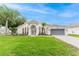Charming single-story home with lush lawn, palm trees, and elegant white facade at 10001 Newington Dr, Orlando, FL 32836