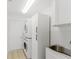 Practical laundry room with stacked washer/dryer, storage cabinets, and a utility sink at 10001 Newington Dr, Orlando, FL 32836