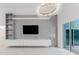 Gray and white living room with entertainment center, contemporary lighting, and glass doors to pool at 10001 Newington Dr, Orlando, FL 32836