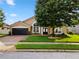 Traditional tan home featuring arched windows, a two-car garage, and a well-manicured front lawn at 1008 Soldier Creek Ct, Oviedo, FL 32765
