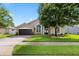 Inviting tan home with a dark garage door, arched windows, and lush green lawn at 1008 Soldier Creek Ct, Oviedo, FL 32765