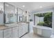 Luxurious bathroom with a soaking tub, double vanity, marble floors, and a view to the outdoor garden at 104 Amberwood Ct, Longwood, FL 32779