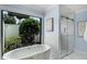 Bright bathroom features a standalone tub beneath a window and a glass enclosed shower with marble surround at 104 Amberwood Ct, Longwood, FL 32779