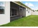 A large backyard with green grass, a screened-in patio, and a white fence at 1091 Wood Dale Cir, Oviedo, FL 32765