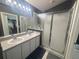 Bathroom featuring double sink vanity, ample counter space, large mirrors and a glass enclosed shower at 11236 Rouse Run Cir, Orlando, FL 32817