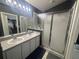 Bathroom featuring a double sink vanity, a large framed mirror, and glass-enclosed shower at 11236 Rouse Run Cir, Orlando, FL 32817
