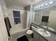 Well-lit bathroom with a tub and shower, vanity with a mirror, and decorative wallpaper at 11236 Rouse Run Cir, Orlando, FL 32817