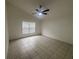 Well-lit bedroom with neutral colors and tile flooring, featuring a large window and ceiling fan at 11236 Rouse Run Cir, Orlando, FL 32817