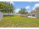 Large grassy backyard with a white fence, mature trees, and a charming patio area at 11616 Thacker Dr, Clermont, FL 34711