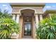 Elegant home entrance featuring stately columns and a decorative glass front door at 13626 Sunset Lakes Cir, Winter Garden, FL 34787
