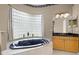 Relaxing bathroom with a deep soaking tub, vanity with black countertop, and privacy window at 13626 Sunset Lakes Cir, Winter Garden, FL 34787