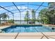 Screened pool with waterfall feature and lake view offers a tranquil outdoor space at 13626 Sunset Lakes Cir, Winter Garden, FL 34787