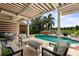 Relax on the covered patio with comfortable seating overlooking the pool, hot tub, and beautifully landscaped yard at 14744 Spotted Sandpiper Blvd, Winter Garden, FL 34787