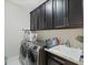 Laundry room with dark wood cabinets for storage, stainless steel washer and dryer, and utility sink at 14744 Spotted Sandpiper Blvd, Winter Garden, FL 34787