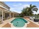 Backyard pool with travertine tile, spa, poolside seating, palm trees, and beautiful landscaping at 14744 Spotted Sandpiper Blvd, Winter Garden, FL 34787