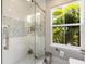 Bright bathroom shower with elegant tiling, glass doors, and a view of lush greenery at 14744 Spotted Sandpiper Blvd, Winter Garden, FL 34787