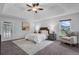 Bright main bedroom featuring a tray ceiling, ceiling fan, and a comfortable seating area at 15038 Willow Ln, Tavares, FL 32778