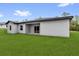 Rear view of the home shows the backyard with plush green grass and the home's neutral colors at 17501 Sw 41St Cir, Ocala, FL 34473