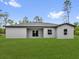 Exterior back view of the home with green lawn, dark roof, and white exterior at 17501 Sw 41St Cir, Ocala, FL 34473