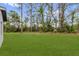 A lush green backyard featuring a picturesque tree line under a blue sky with scattered clouds at 17501 Sw 41St Cir, Ocala, FL 34473