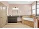 Bright bathroom featuring a vanity with dark cabinets, a soaking tub with tile surround, and a large window at 2051 Sandy Garden Ln, Winter Garden, FL 34787