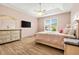Bright bedroom featuring wood floors, a ceiling fan, a TV, and a decorative dresser with a large mirror at 2051 Sandy Garden Ln, Winter Garden, FL 34787