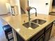 Close up of kitchen island with stainless steel sink, faucet, granite countertop, and bar seating for a functional layout at 2051 Sandy Garden Ln, Winter Garden, FL 34787